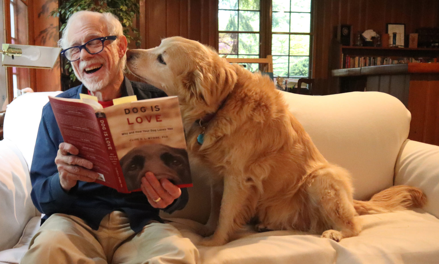 Buddy and Millie reading "DOG IS LOVE " book on the couch