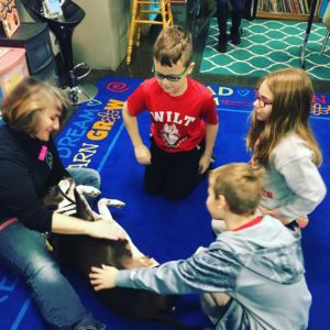 School children group around a therapy team for petting